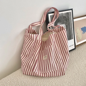 Detail of red and white striped canvas tote bag with front pocket and fabric label