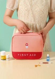 Detail of pink and red first aid kit with top handle and printed cross icon for travel