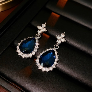 Macro detail of silver drop earrings with dark blue pear-shaped stone and crystal pavé