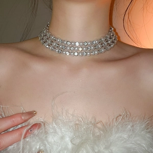 Close-up of triple-layer pearl choker with sparkling rhinestone accents on a model