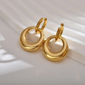 Close-up of golden double-hoop chunky earrings on a white minimalist display