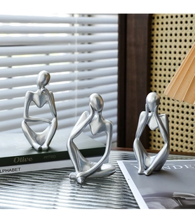 Modern silver thinker statues on glass surface with elegant minimalist room decor
