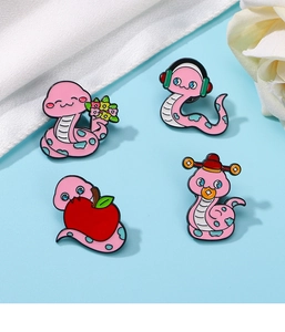 Detailed view of four pink cartoon snake enamel brooches with floral and apple motifs