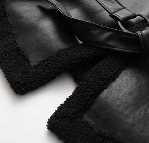 Close-up of black leather texture with plush faux fur trim and metal buckle detail