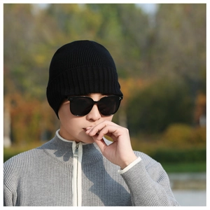 Detail shot of black knitted beanie with vertical ribbed texture on a male model outdoors