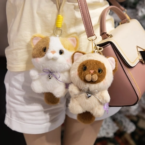 Cute plush cat keychains with ribbon and heart pendant hanging on a stylish handbag