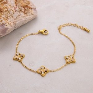 Macro detail of 18k gold clover bracelet featuring white zircon stones and fine chain