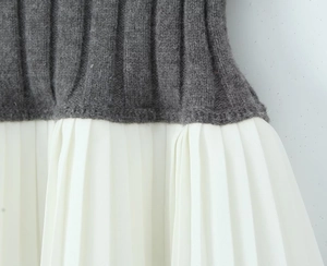 Detailed macro view showing grey knitted fabric contrast with white pleated skirt hem