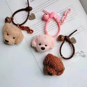 Cute plush teddy dog head charms with bells and heart pendants on book background