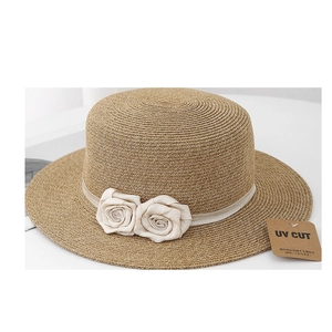 Detailed view of woven straw sun hat with decorative fabric roses and satin ribbon