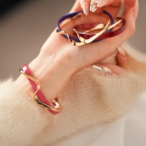 Detail showing the elegant double-layer wavy gold bangle with colorful resin inlay