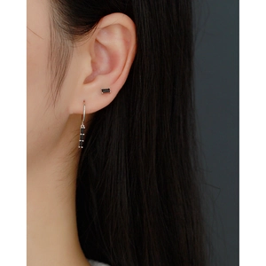 Detail view of silver S925 earrings with black rectangular crystals on a female model