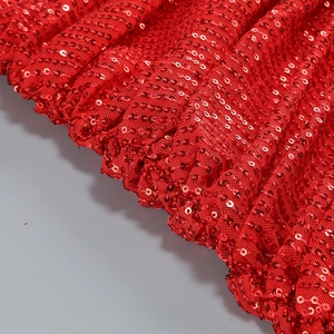 Detailed close-up of shiny red sequins and pleated mesh fabric on a party dress