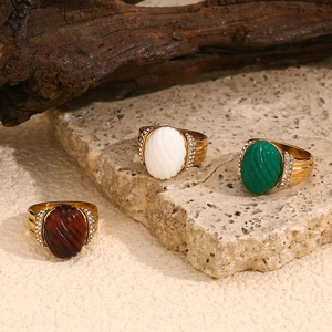 Detailed macro view of 18K gold-plated rings with oval acrylic stones on stone display