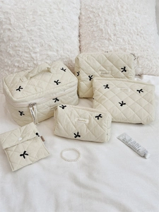 5-piece set of beige quilted toiletry bags featuring black bow embroidery detail