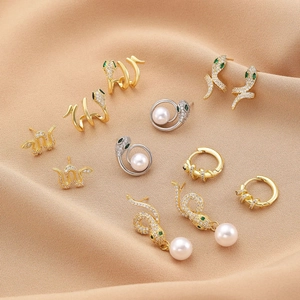 Set di orecchini a serpente oro e argento con zirconi bianchi e perle su tessuto