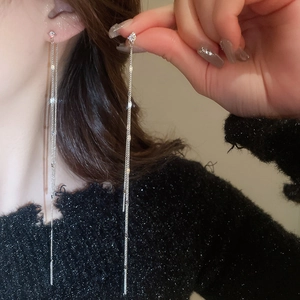 Macro detail of long silver tassel earrings with multiple chains and sparkling zircons