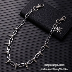 Detail of silver punk waist chain with sharp spikes and star pendant on leather background