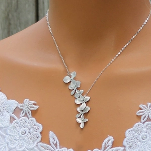 Vue détaillée du collier de pétales en argent mat porté sur une robe en dentelle blanche