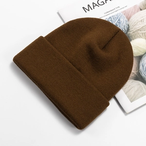 Close-up of dark brown knit beanie with fold-over cuff on a magazine background