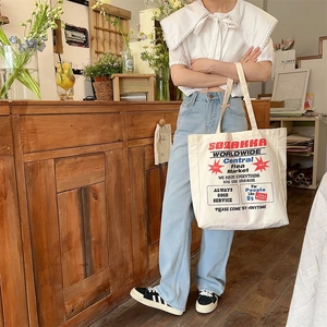 Detail of vintage canvas tote bag featuring red graphic print on a wooden counter