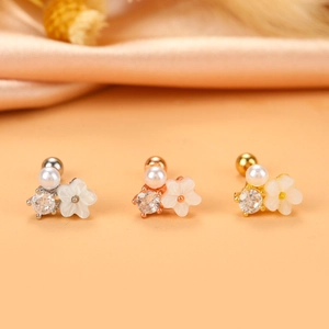 Detailed macro view of cross-style shell flower earrings in silver, gold, and rose gold