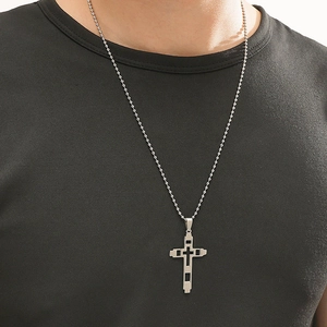 Close-up of a silver stainless steel hollow cross pendant worn by a male model