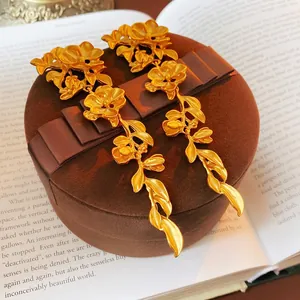 Vintage golden long flower leaf tassel earrings on a velvet jewelry box and book