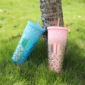 Close-up of pink and blue gradient studded cups with diamond texture on a grass lawn