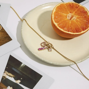 Gold stainless steel heart necklace with pink zircon pendants on a ceramic plate