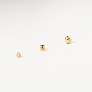 Detailed view of three golden hammered texture stainless steel spacer beads in various sizes