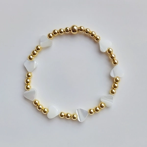Detailed macro view of 18K gold-plated beads and natural shell heart-shaped charms