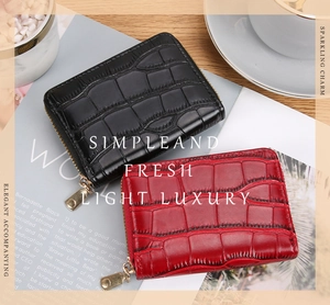 Detail view of crocodile textured card holders in black and deep red with gold zippers