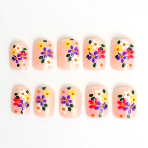 Detailed view of short square press-on nails with colorful floral patterns on nude pink base