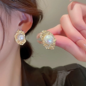 Close-up of vintage gold lava texture earrings with iridescent pearl inlays on a model