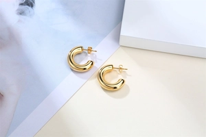 Detailed macro view of gold-colored C-shaped hoop earrings with polished metal finish