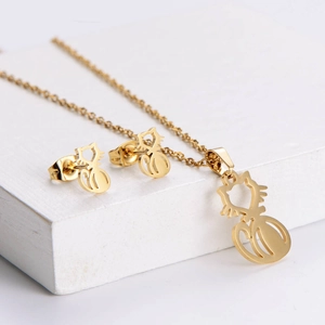 Golden hollow cat pendant necklace and stud earrings jewelry set on a white tray