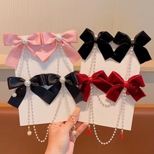 Detail of velvet bow hair clips with pearls and long metal tassels in red black and pink