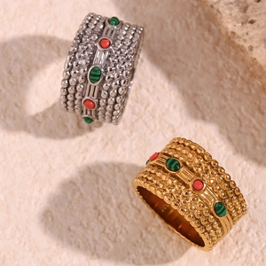 Detail of bohemian rings with beaded texture and red green gemstones in gold and silver