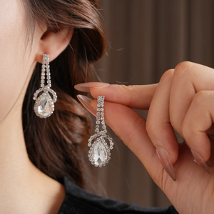 Close-up of sparkling teardrop-shaped drop earrings with silver-toned rhinestone setting