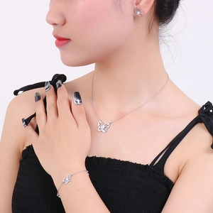 Detailed view of silver butterfly jewelry set with pearls on model featuring earrings