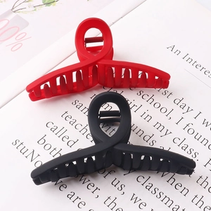 Close-up of matte red and black large hair claws on vintage book pages for accessory detail