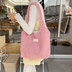 Pink plush reversible tote bag featuring a minimalist white brand label and soft texture