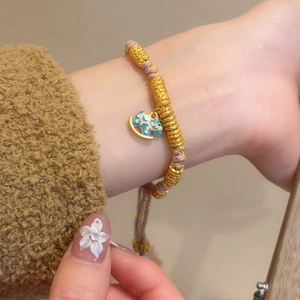 Close-up of golden beaded bracelet with blue enamel rocking horse charm on wrist