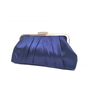 Detailed close-up of dark blue satin evening bag with pleated fabric and rhinestone clasp