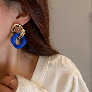 Detail of Klein blue and gold chain link earrings on model with elegant geometric style