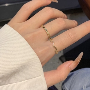 Detail shot of gold-plated twisted rope and wavy zircon rings worn on a hand