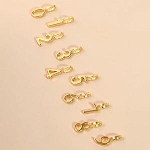 18K gold plated number charms 0-9 for DIY jewelry making on a beige background