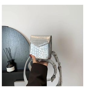Détail macro du mini sac bandoulière argenté avec texture crocodile et finition brillante