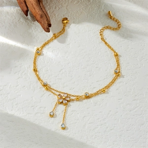 Double-layered gold flower anklet with sparkling crystal tassels on a natural wood surface